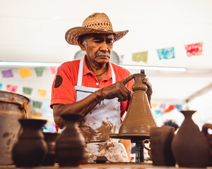 A mexican old man working on pottery with his hands