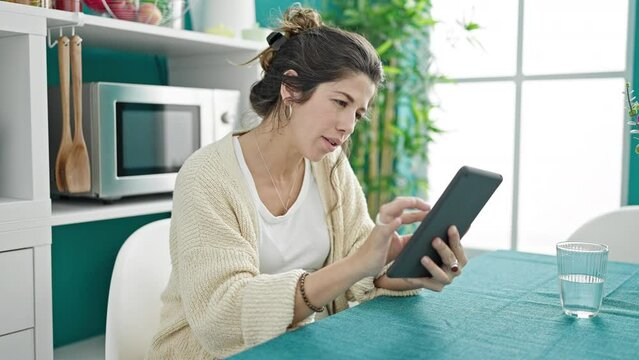 Young pregnant woman touching belly using touchpad at dinning room