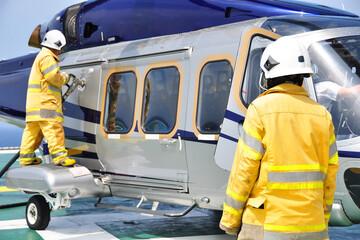 Helicopter Landing Officer communicating with pilot and copilot for service on ground and support as the pilot required. The helicopter landing on the deck and service by ground service team. - obrazy, fototapety, plakaty
