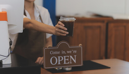 Welcome. Open. barista, waitress woman turning open sign board on glass door in modern cafe coffee...