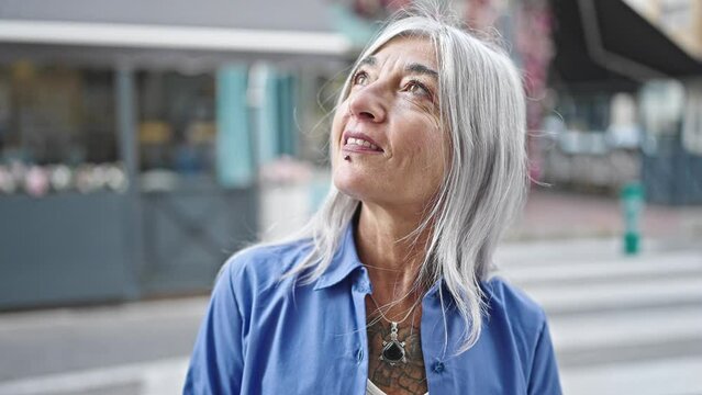 Middle age grey-haired woman smiling confident standing at coffee shop terrace