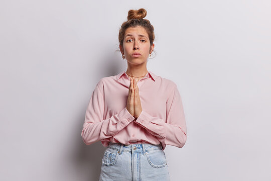 Female presses her hands together in prayer with expression of longing she pleads with God pouring her heart out seeking fulfillment of deepest dream leaving profound impression of vulnerability