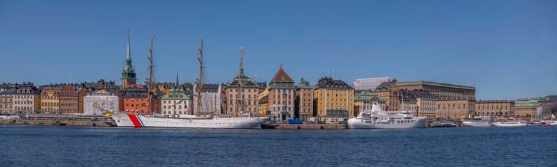 Large sailing ship, US coast guard, ferries and sightseeing boats at the pier in the old town Gamla Stan, a sunny summer day in Stockholm