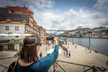 femme prenant en photo avec son téléphone le Pont Dom Luis  qui traverse la rivière du Douro à...