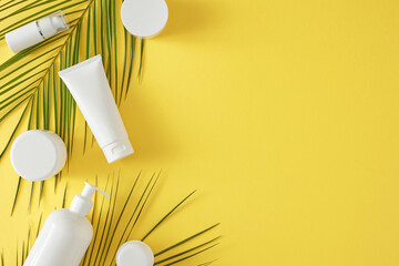 Skincare routine for summer vacation.Top view flat lay of cosmetic bottles without label and palm leaves on yellow background with empty space for text or advert