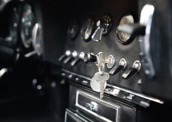 Vintage car dashboard or cockpit with key in ignition. Classic or sports car. Instruments and switches of high performance muscle car or coupe. Automobile history. Selective focus. Dark background