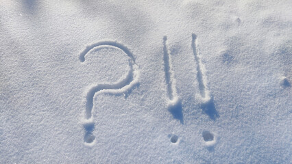 Question mark and exclamation mark on snowy surface close-up. Copy space. Confusion situation