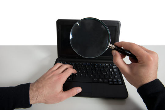 Hacker looking for a password in a laptop with magnifier lens