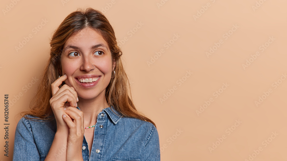 Wall mural studio shot of pretty young woman has focused gaze and dreamy expression creates intriguing aura sta