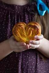 Little girl holding homemade sugar bun in her hands. Close up - 612066762