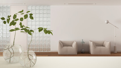 White table top or shelf with glass vase with hydroponic plant, ornament, root of plant in water, branch in vase,bathroom with grass brick wall, interior design