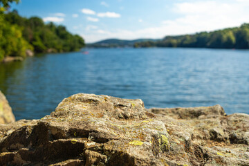 Fototapeta na wymiar Panorama of a natural body of water with a rock in the foreground in a forest landscape. Brno Reservoir - Czech Republic.