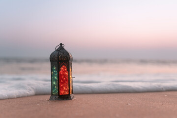 Lantern lamp on the beach with sunset background, Ramadan Kareem and Eid Mubarak greeting concept image
