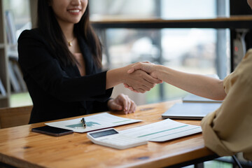 Recruiter shaking hands with a young female candidate after a job interview.