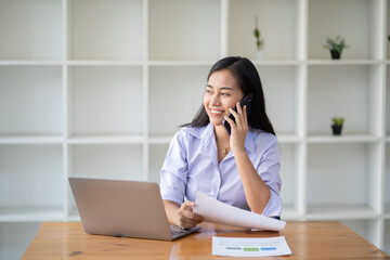 Asian businesswoman playing with mobile phone inside modern office