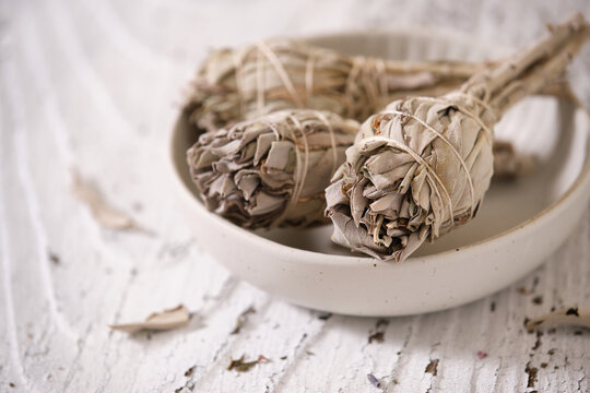 White Sage smudge sticks (Salvia apiana) in a white bowl on an old white wooden table