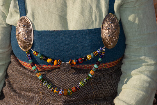 Richly decorated gilded viking brooches with string of colorful glass beads.