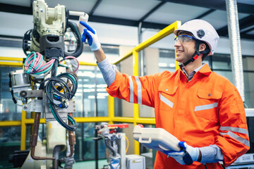 Engineers team mechanic using computer controller Robotic arm for welding steel in steel factory workshop. Industry robot programming software for automated manufacturing technology