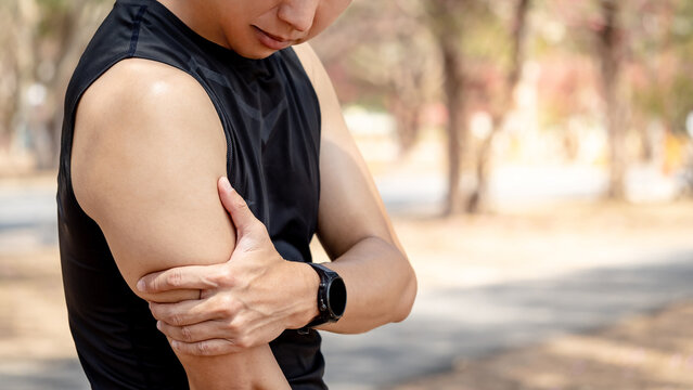 Bicep tendonitis or front arm muscle inflammation. Asian athlete man suffering from upper arm pain while doing outdoor exercise in the park. Sport injury concept.