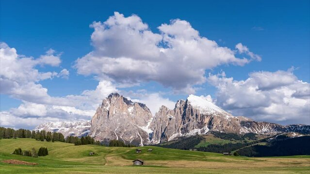 Time-lapse video of clouds passing snow-capped mountains and lush alpine meadows. Langkofel and Plattkofel dominate the landscape. Seiser Alm (Alpe di Siusi) in the Dolomites, South Tyrol, Italy.