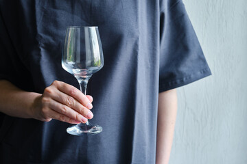 A glass of white wine in the hands of a girl. Tasting of alcoholic beverages. Summer rest. Romantic evening aperitif. Close-up of a glass of wine. Enjoy the moment