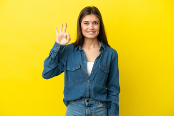 Young caucasian woman isolated on yellow background showing ok sign with fingers