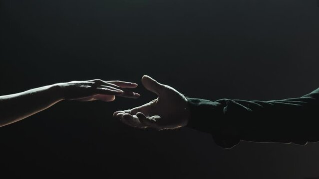 Lovers hold each other's hands on a dark background. Closeup romantic people touching hands outside.