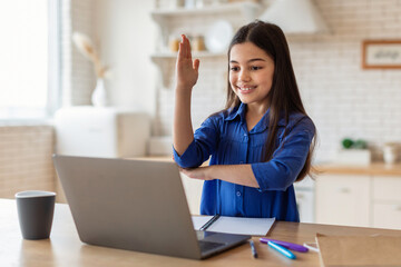 Schoolgirl Raising Hand During Video Call On Laptop At Home