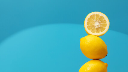 A pyramid of juicy yellow lemons on a blue background. Creative concept of fruits, citrus fruits. 