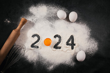 Creative Happy New Year 2024 greeting card for home baker. Numbers made out of flour with egg yolk,...