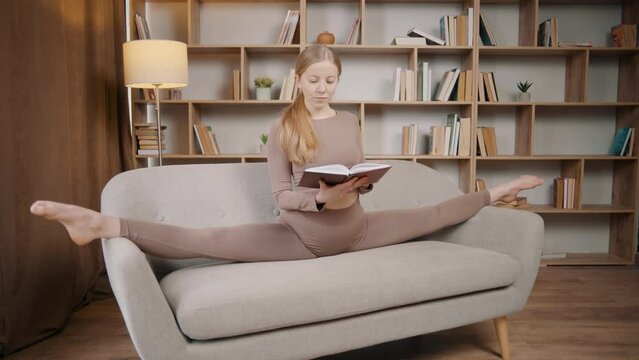 Young girl is doing yoga in a room with books, the girl stretches with a notebook in her hands