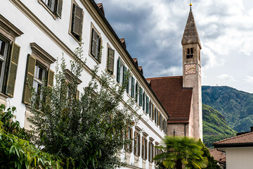 A church with narrow tower in the middle of the city of bolzano