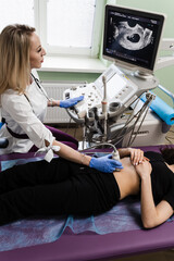 Pregnancy and maternity. Gynecologist conducts ultrasound scan for pregnant young woman on early...