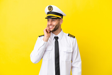 Airplane caucasian pilot isolated on yellow background thinking an idea while looking up