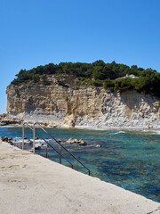 Ladder entering the turquoise water of the Mediterranean sea in Cala Advocat, Cove of L'Advocat....
