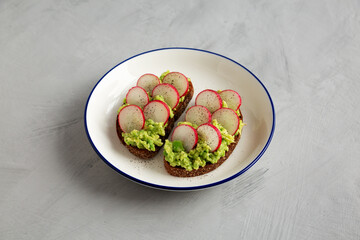 Homemade Radish Avocado Toast with Salt and Pepper on a Plate, side view.