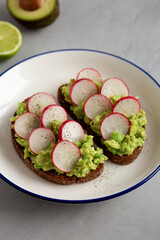 Homemade Radish Avocado Toast with Salt and Pepper on a Plate, side view.