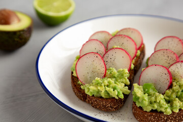 Homemade Radish Avocado Toast with Salt and Pepper on a Plate, side view.