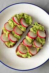 Homemade Radish Avocado Toast with Salt and Pepper on a Plate, top view. Close-up.