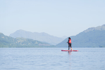 Single female on a stand up paddle board during a summer morning