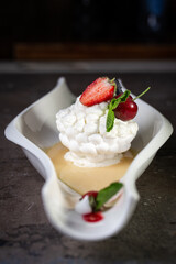 sweet meringue dessert with strawberry berries close-up on a dark background