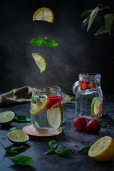 Fresh strawberry lemonade with lime and lemon and basil leaves on dark background 