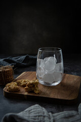 Glass with ice cubes for iced latte with cookies on wooden board 
