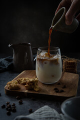 Glass of iced latte with cookies on dark background 