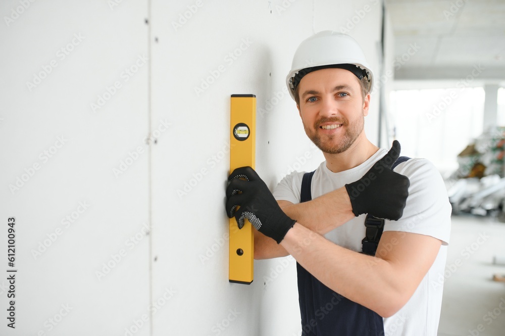 Wall mural Portrait of positive, handsome young male builder in hard hat.