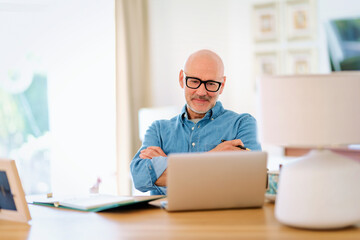 Mid aged man sitting at home and having web conference