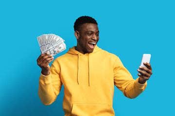 Thrilled black guy holding smartphone and cash