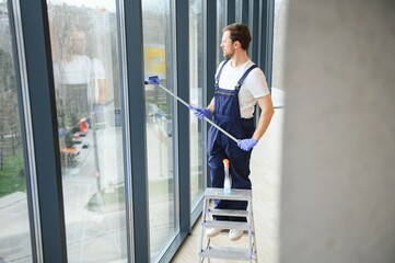 Fototapeta na wymiar Male worker washing window glass