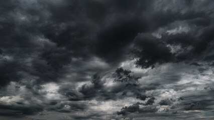 dark dramatic sky with black stormy clouds before rain or snow as abstract background, extreme weather, the sun shines through the clouds, high contrast photo