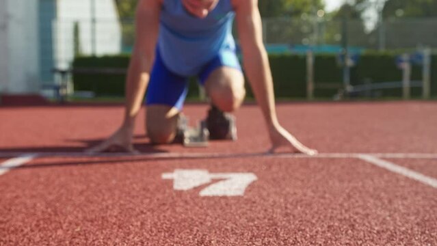 Focused young professional male Caucasian athlete ready for the run race in a sprint starting position, zoom shot.